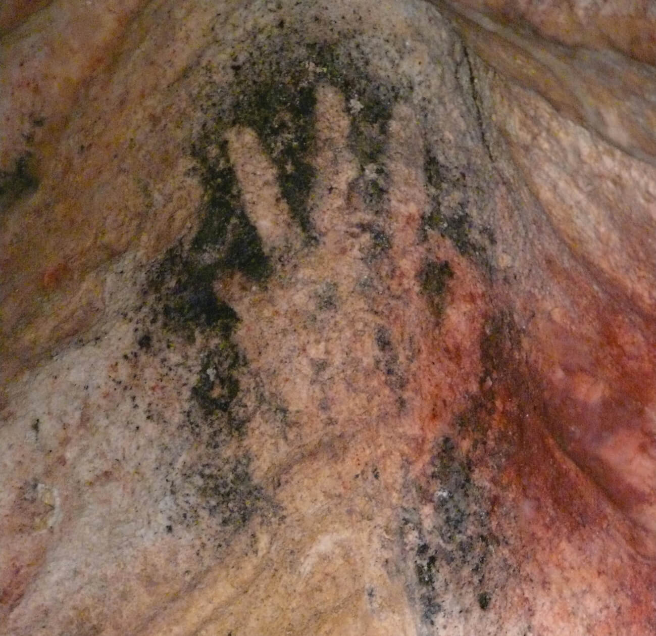 An image of a cave painting, circa twenty five thousand BC, depicting the shape of a human hand. The painting is located near the town of Gargas in the Luberon area of France, which is also home to a number of mines that produce sienna. 