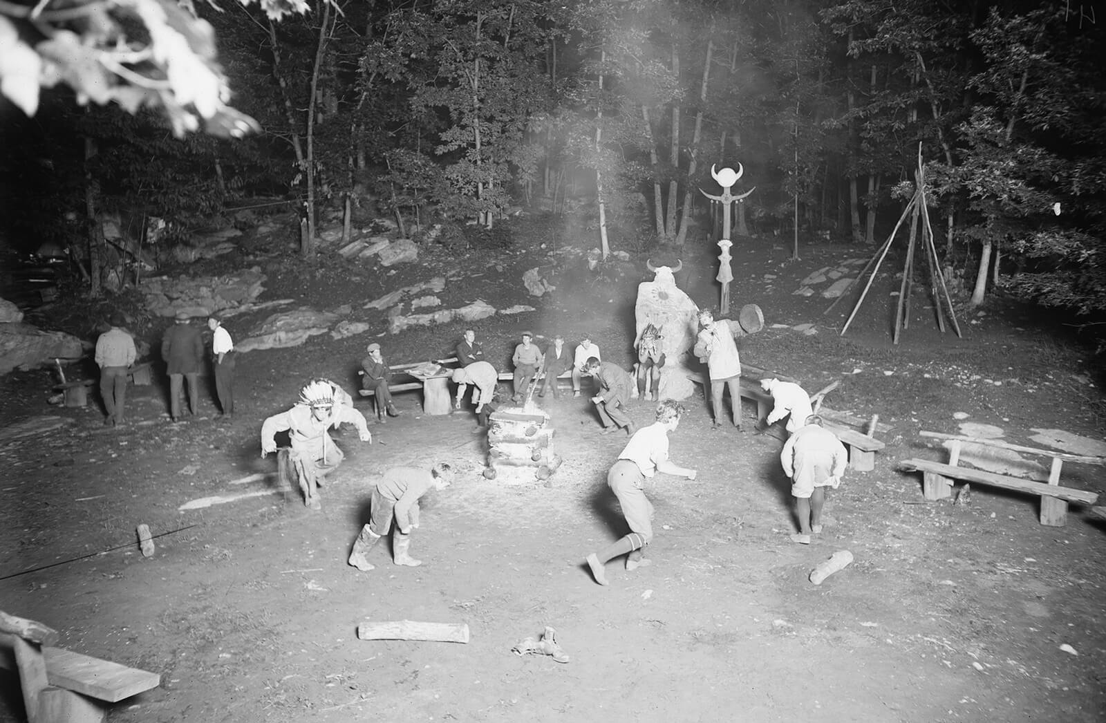 A photograph of a group of men enacting the Native “War dance” within a woodland area at Wyndygoul, Seton’s estate near Cos Cob, Connecticut, date unknown.