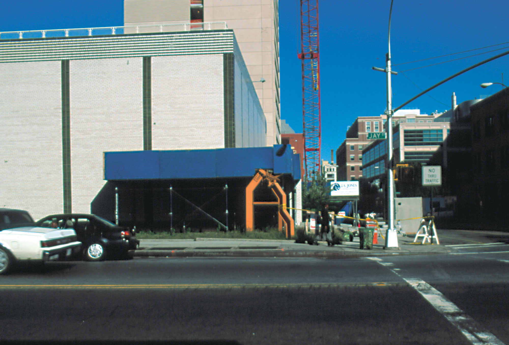 A photograph of a street in Brooklyn showing Allen Mooney's sculpture “Iroquois Walk” underneath a construction scaffold.