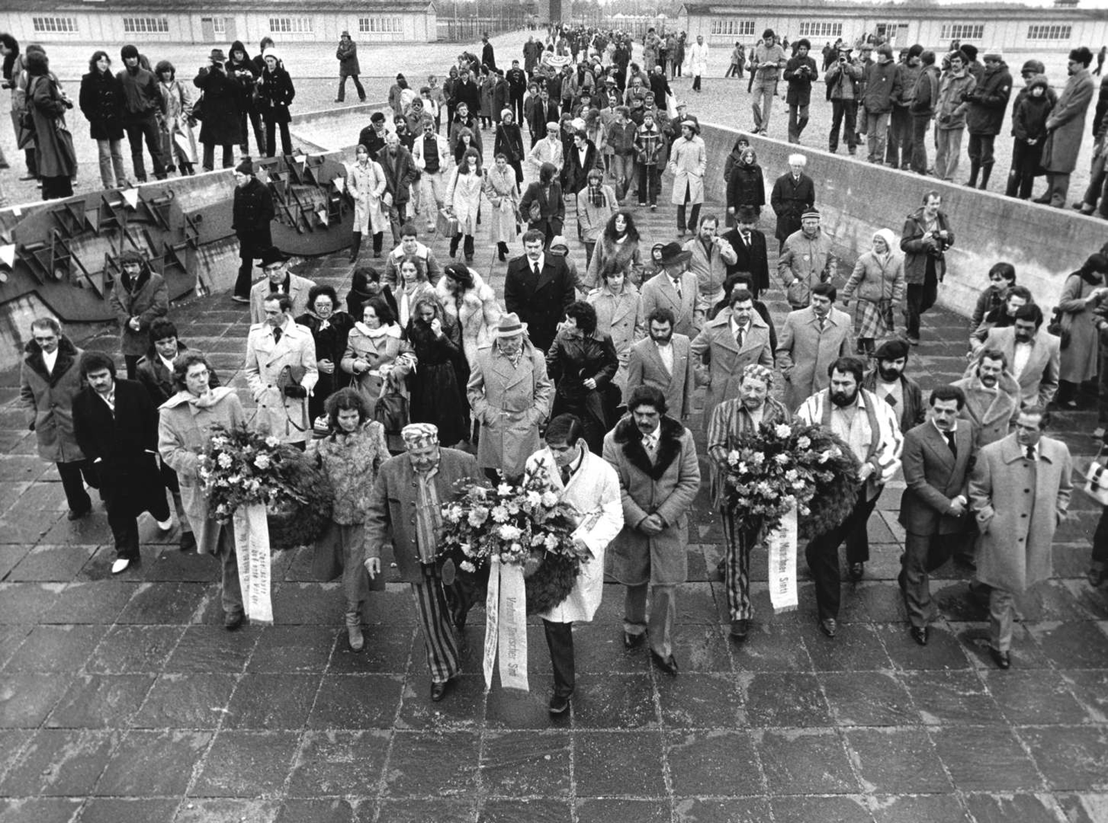 A group of people holding wreaths for a ceremony for the Sinti and Roma murdered at Dachau.