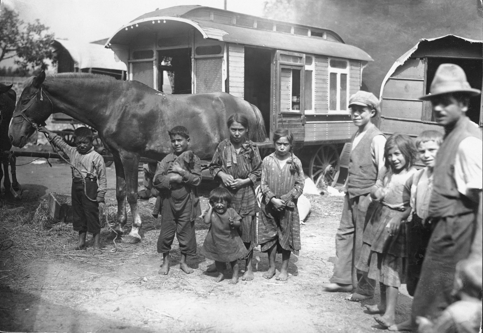 A group of Romani in front of a caravan.