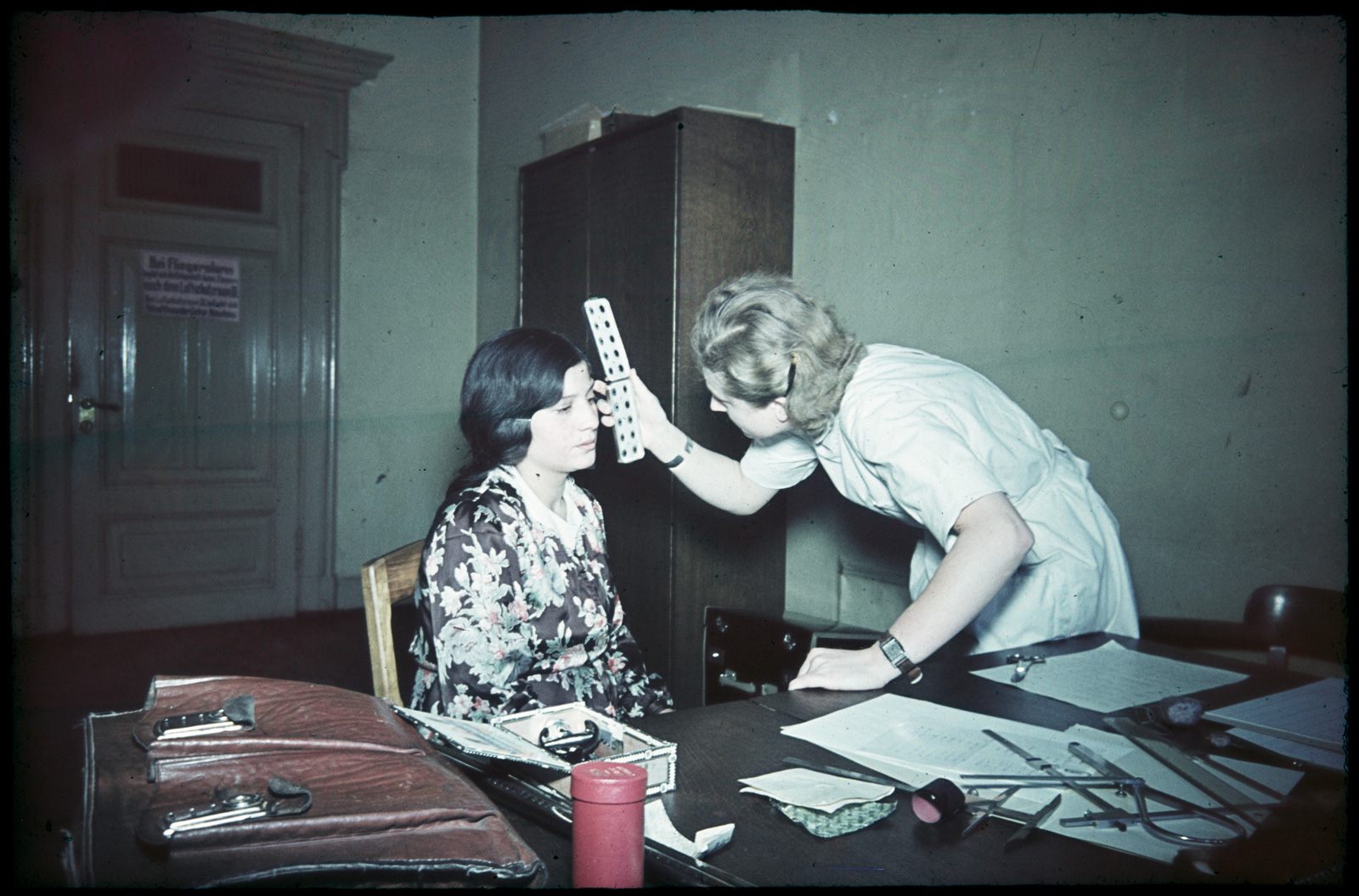 A woman testing the eye color of another woman in a laboratory setting.