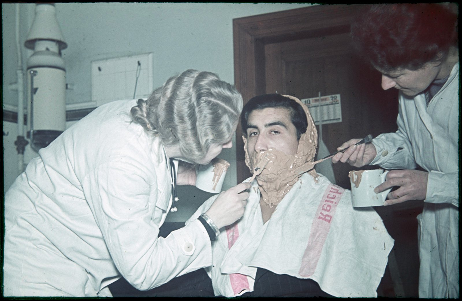 Two women taking the mold of a man’s face in a laboratory setting.