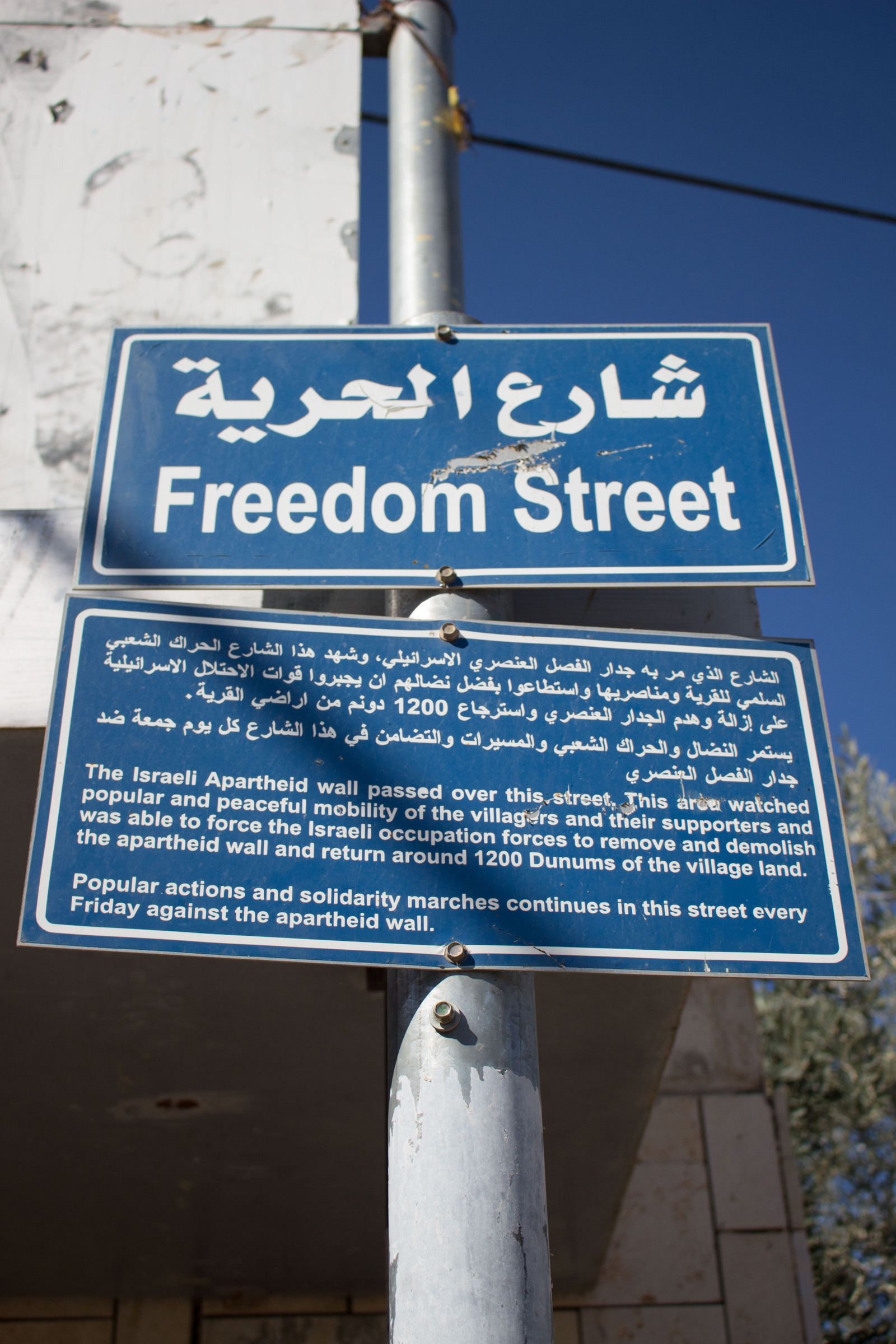 Photograph of a street sign in the village of Bil’in celebrating the restoration of access to some three hundred acres of its farmland previously cut off by Israel’s separation wall.