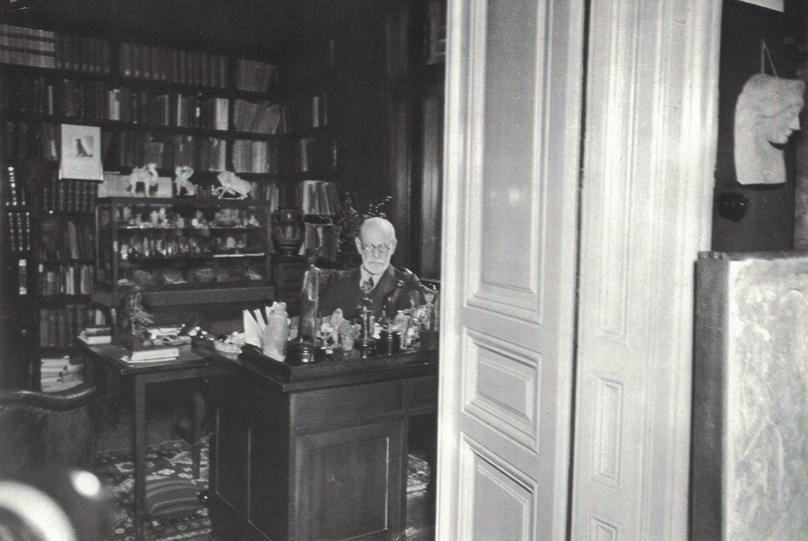 A photograph of Freud in his office, glimpsed through a doorway.