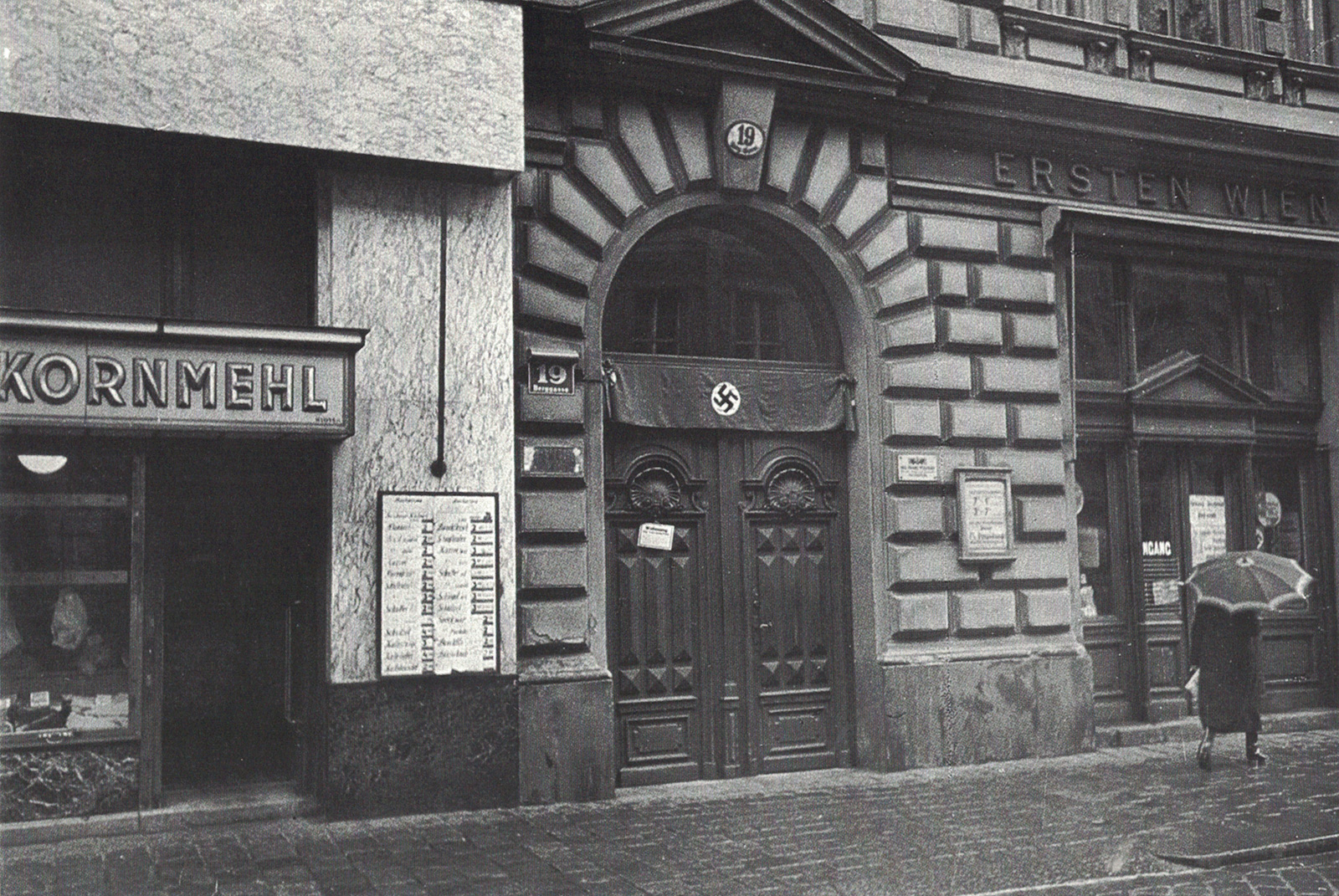 A photograph of the exterior door of Berggasse nineteen, with a swastika banner mounted above.