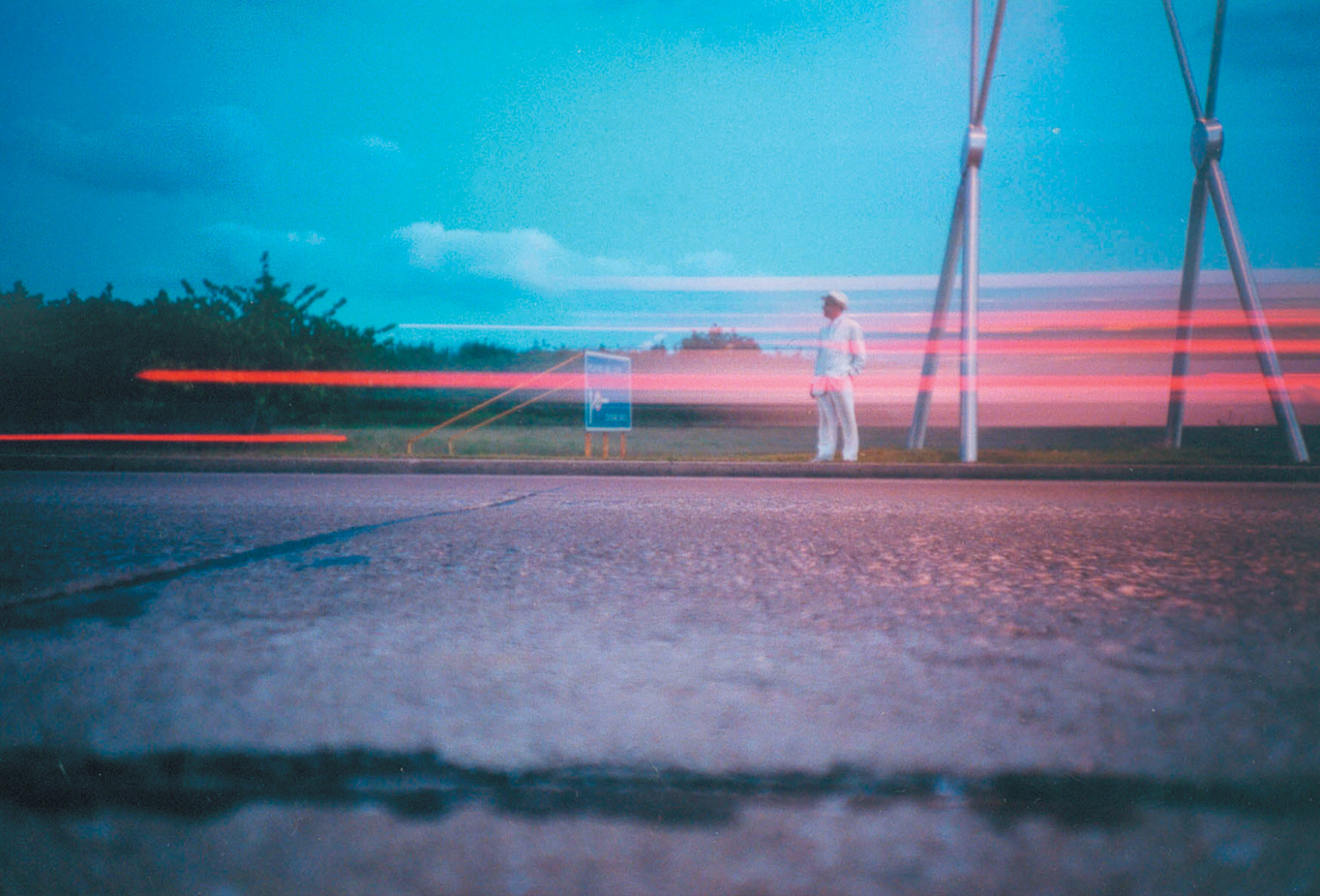 A Lomographic image depicting a man standing next to a road.